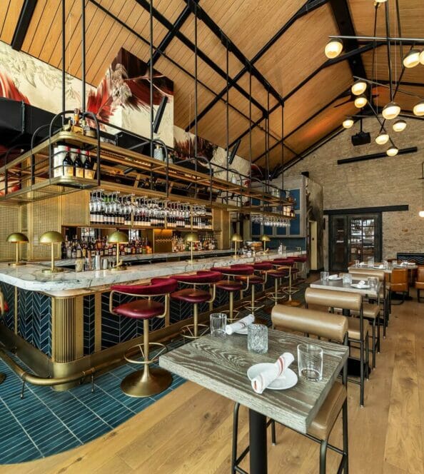 a glamorous lounge in a historic building with gold and crimson stools around a marble bar
