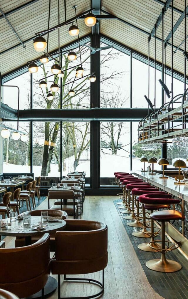 a glamorous lounge in a historic building floor to ceiling a-frame windows looking out on a snowy landscape
